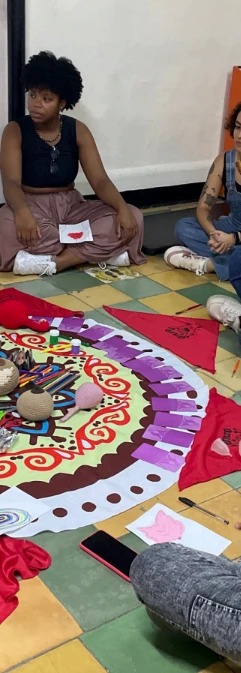 Participante sentada junto a un mándala con telas rojas en un taller de educación sexual integral